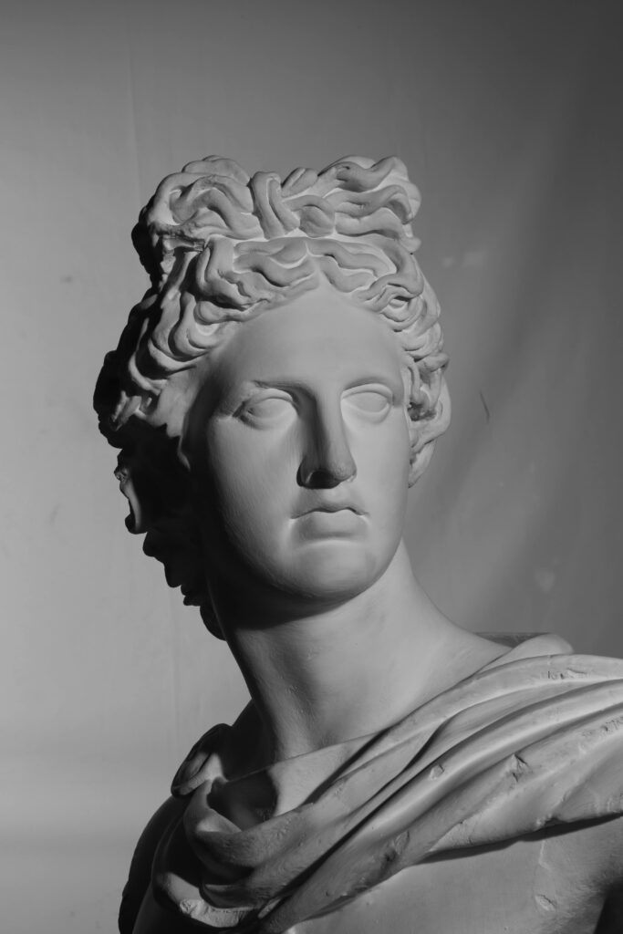 Monochrome image of an ancient Greek-style sculpture bust, dramatic lighting emphasizes details.